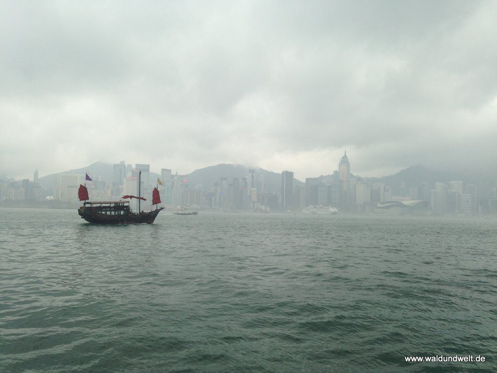 Nebelverhangene Skyline von Hong Kong Island mit chinesischem Boot im Vordergrund